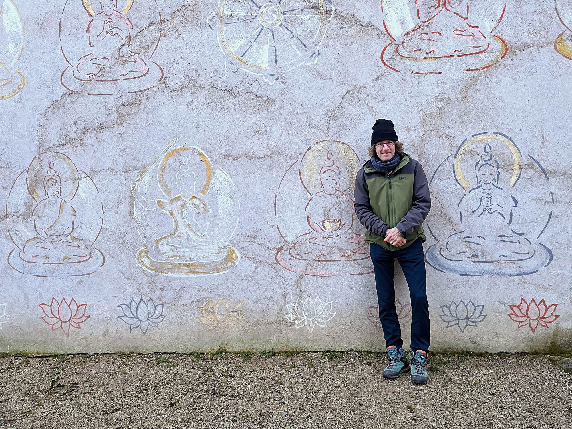 White Wolf Healing - Theodoor Vink Theodoor staat voor een muur beschilderd met mooie Buddha's